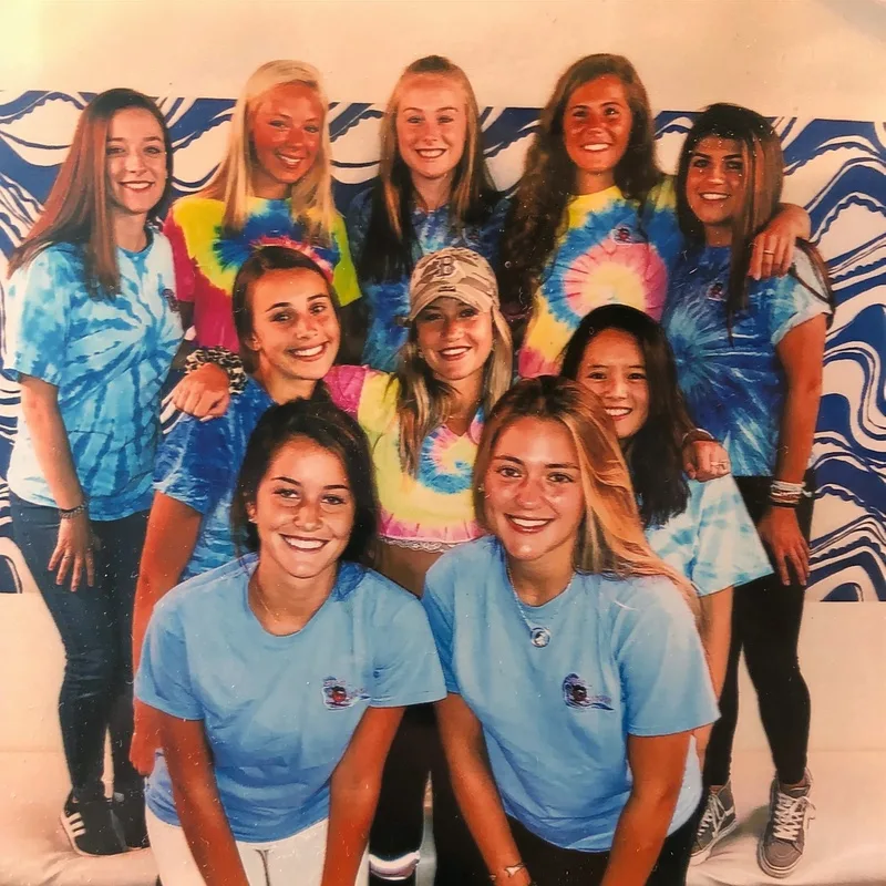 The Sweet Waves crew posing together in tie-dye shirts in front of a blue and white wave backdrop